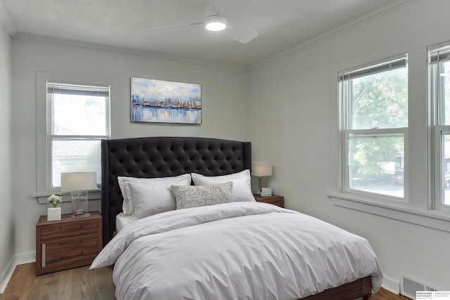 bedroom with multiple windows, wood-type flooring, ceiling fan, and crown molding