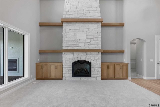 unfurnished living room featuring light carpet, a fireplace, and a high ceiling