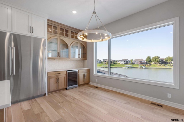 kitchen with pendant lighting, wine cooler, stainless steel refrigerator, and plenty of natural light