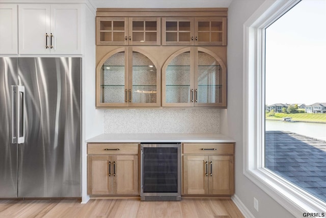 bar featuring wine cooler, high end fridge, and a healthy amount of sunlight