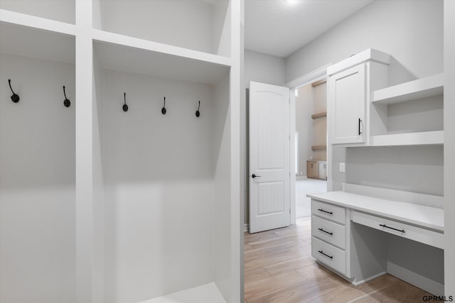 mudroom with built in desk and light wood-type flooring