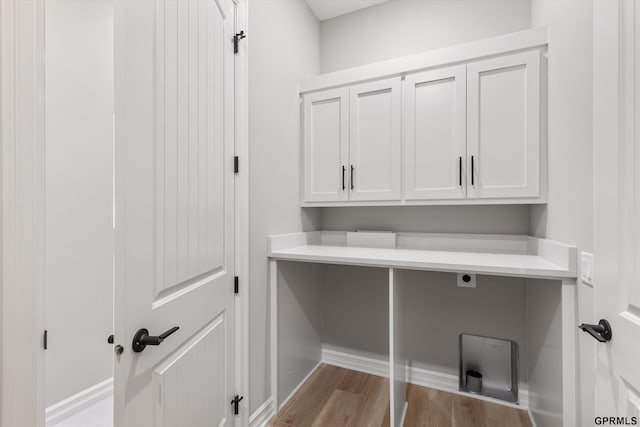 clothes washing area with cabinets, light wood-type flooring, and electric dryer hookup