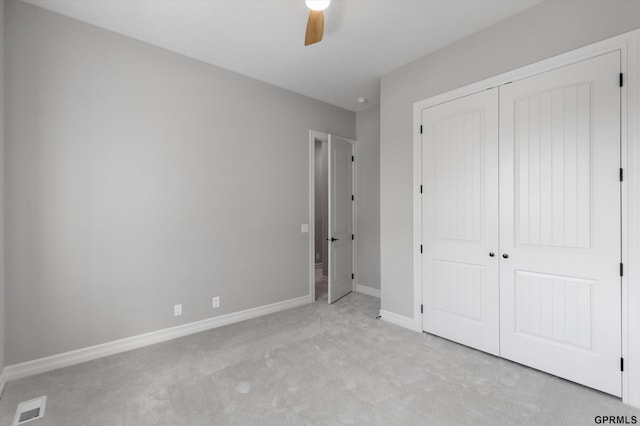 unfurnished bedroom featuring ceiling fan, light carpet, and a closet