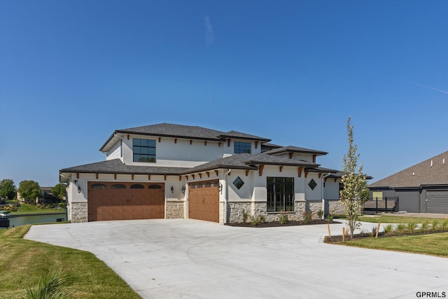 prairie-style home featuring a garage, a water view, and a front lawn