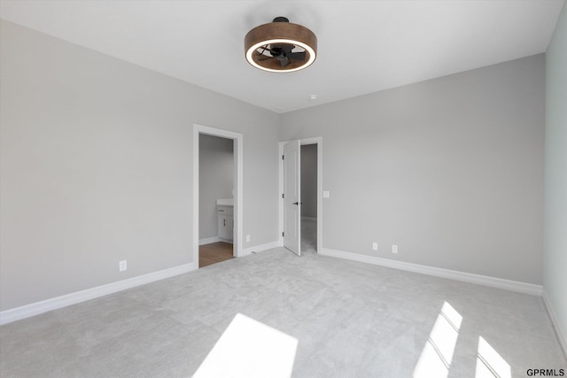 unfurnished bedroom featuring connected bathroom and light colored carpet