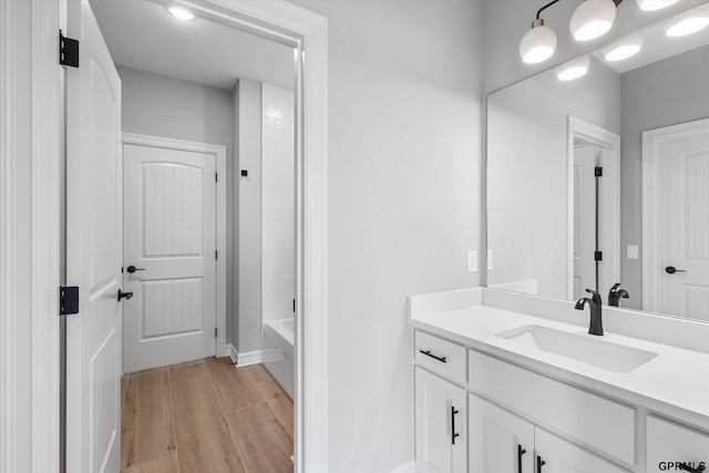 bathroom with hardwood / wood-style floors, vanity, and washtub / shower combination