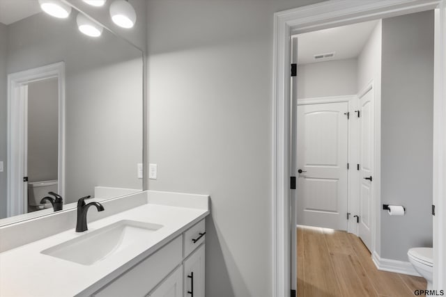 bathroom featuring vanity, hardwood / wood-style flooring, and toilet