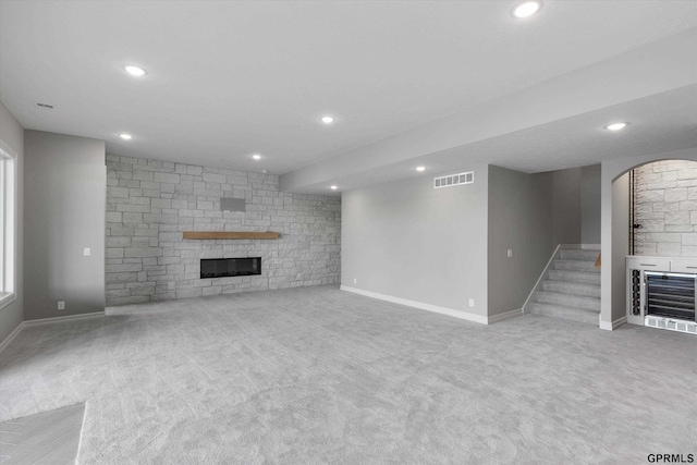 unfurnished living room with heating unit, light carpet, and a fireplace