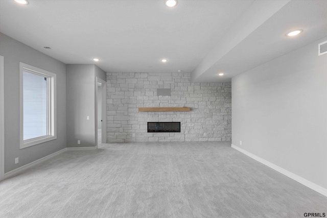 unfurnished living room featuring carpet and a stone fireplace