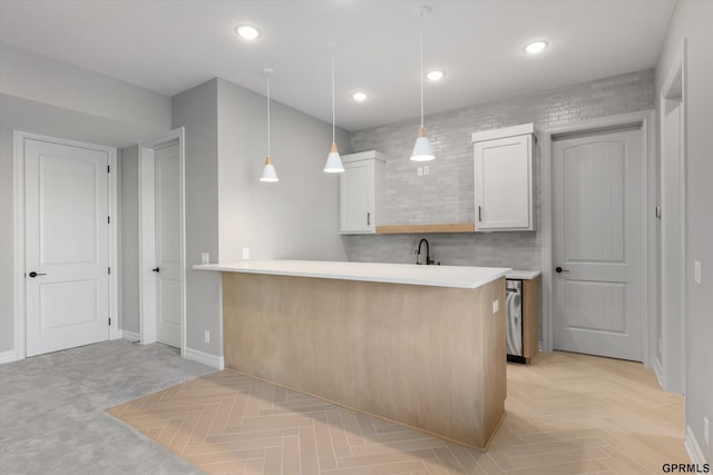 kitchen featuring kitchen peninsula, sink, light parquet flooring, white cabinetry, and hanging light fixtures