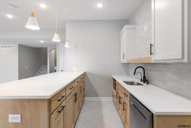 kitchen with pendant lighting, sink, stainless steel dishwasher, light stone counters, and white cabinetry