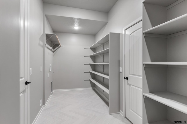 walk in closet with light parquet floors