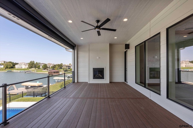 wooden deck featuring ceiling fan, a fireplace, and a water view