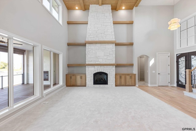 unfurnished living room with a healthy amount of sunlight, wood ceiling, and high vaulted ceiling