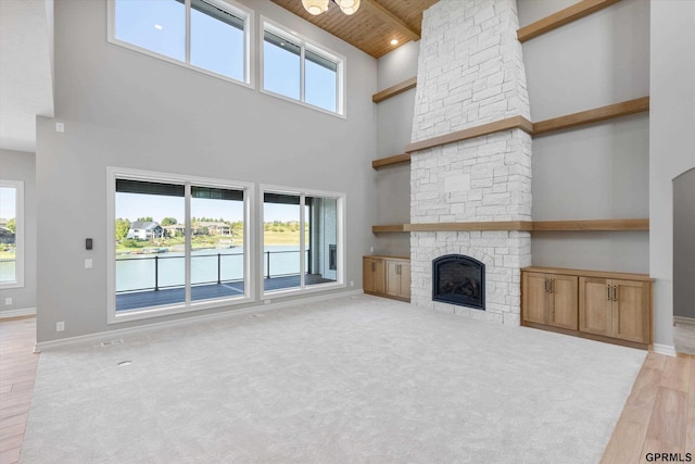 unfurnished living room with plenty of natural light, light hardwood / wood-style floors, wood ceiling, and high vaulted ceiling