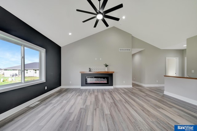 unfurnished living room with ceiling fan, high vaulted ceiling, and light wood-type flooring