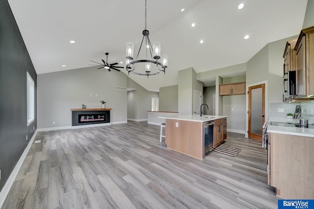 kitchen with light hardwood / wood-style floors, high vaulted ceiling, and a kitchen island with sink