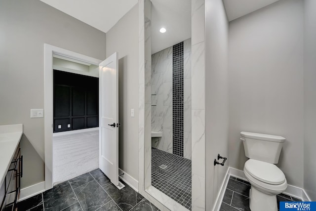 bathroom featuring a tile shower, vanity, and toilet