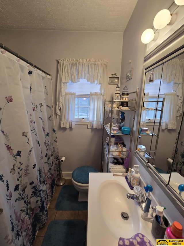 bathroom featuring tile patterned floors, a shower with curtain, sink, toilet, and a textured ceiling