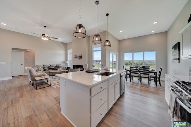 kitchen with white cabinetry, sink, hanging light fixtures, a center island with sink, and appliances with stainless steel finishes