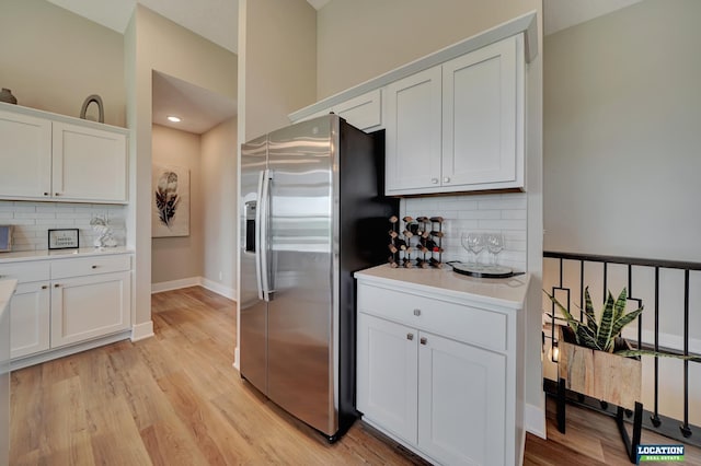 kitchen featuring backsplash, stainless steel fridge, and white cabinets