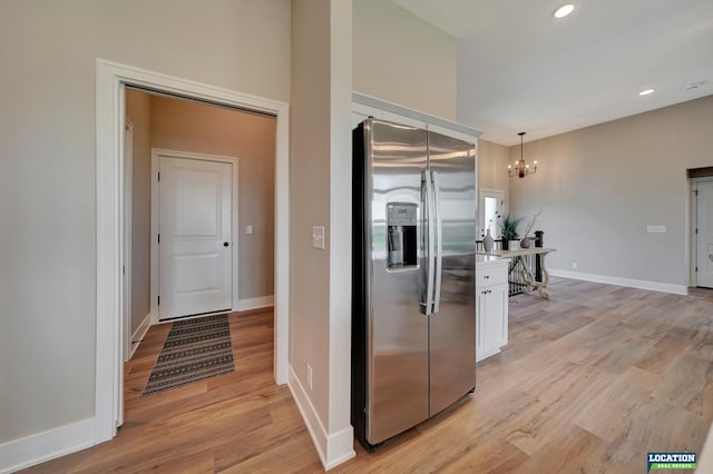 kitchen with white cabinets, stainless steel fridge, light wood-type flooring, and pendant lighting