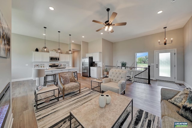 living room featuring sink, light hardwood / wood-style floors, and ceiling fan with notable chandelier