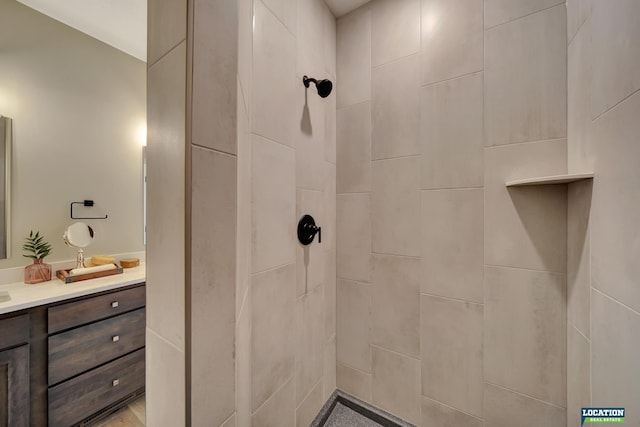 bathroom with tiled shower and vanity