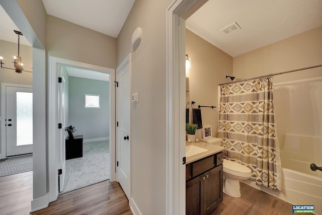 full bathroom featuring a notable chandelier, shower / bath combination with curtain, toilet, vanity, and hardwood / wood-style flooring