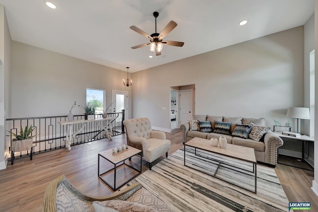 living room with light hardwood / wood-style flooring and ceiling fan with notable chandelier