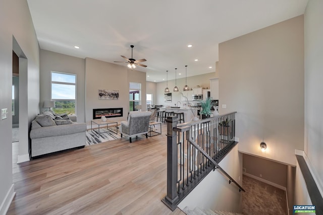 living room with ceiling fan and light hardwood / wood-style flooring