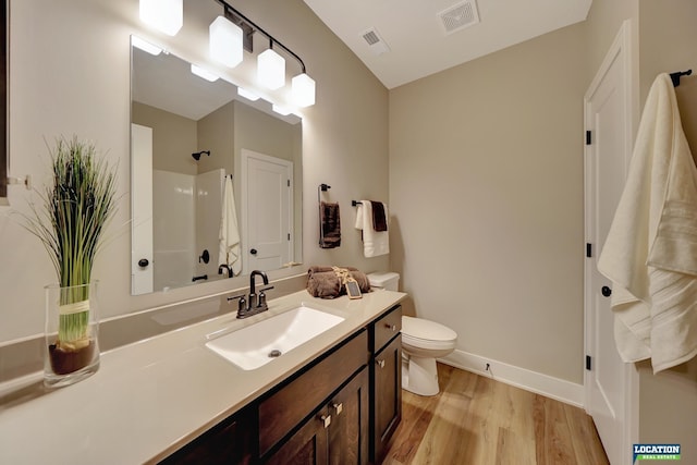 bathroom featuring toilet, vanity, wood-type flooring, and walk in shower