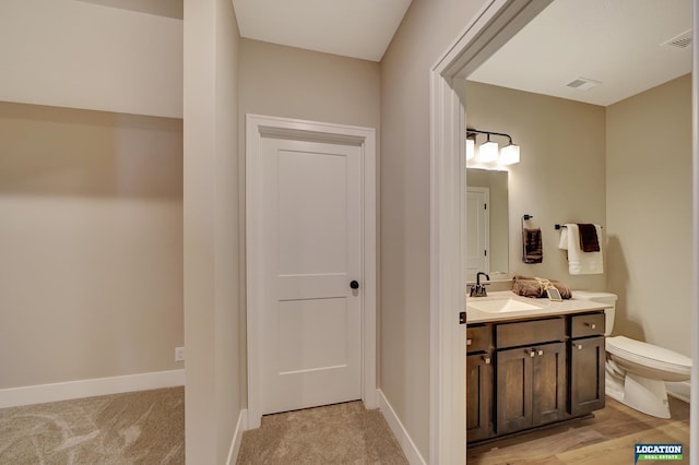 bathroom with wood-type flooring, vanity, and toilet