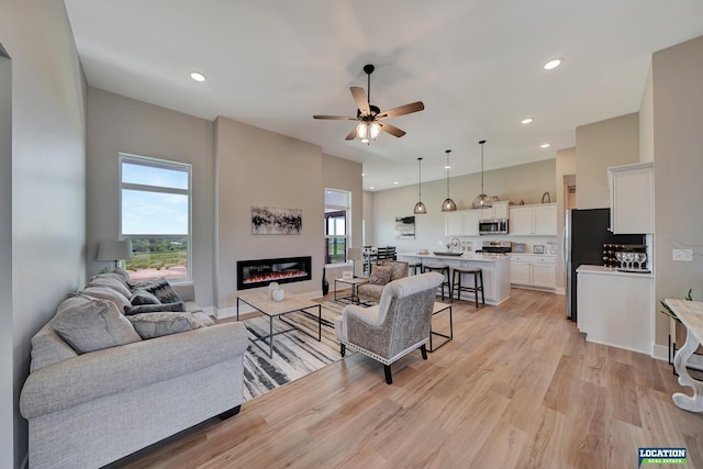 living room with light wood-type flooring and ceiling fan