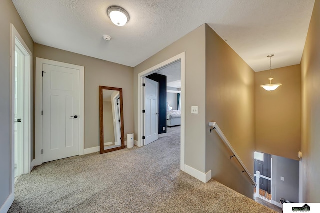 hall featuring carpet and a textured ceiling