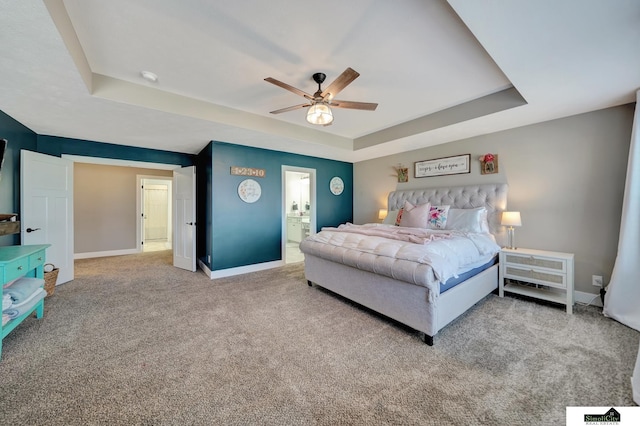 carpeted bedroom with ensuite bathroom, ceiling fan, and a raised ceiling