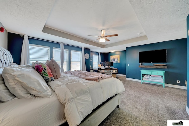 carpeted bedroom featuring a raised ceiling, ceiling fan, and a textured ceiling