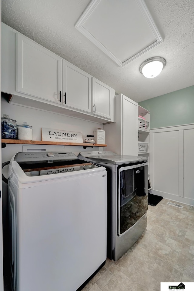 washroom with cabinets, independent washer and dryer, and a textured ceiling