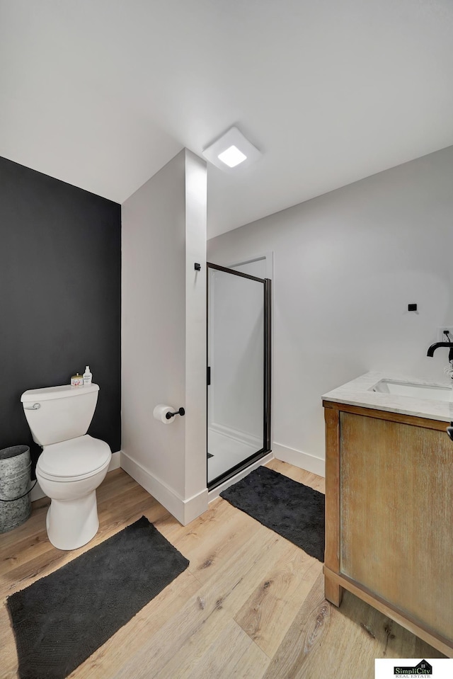 bathroom featuring hardwood / wood-style floors, vanity, a shower with shower door, and toilet