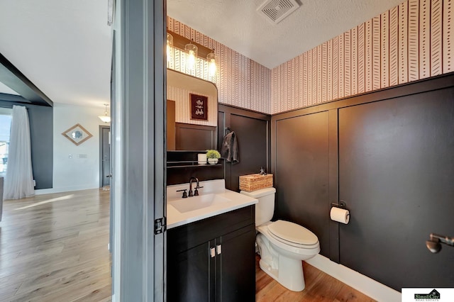 bathroom with hardwood / wood-style floors, vanity, a textured ceiling, and toilet