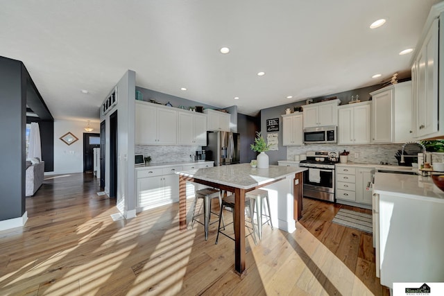 kitchen featuring appliances with stainless steel finishes, light wood-type flooring, white cabinetry, and a kitchen island