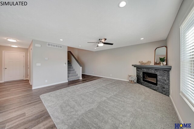 living room with a wealth of natural light, a fireplace, ceiling fan, and light wood-type flooring