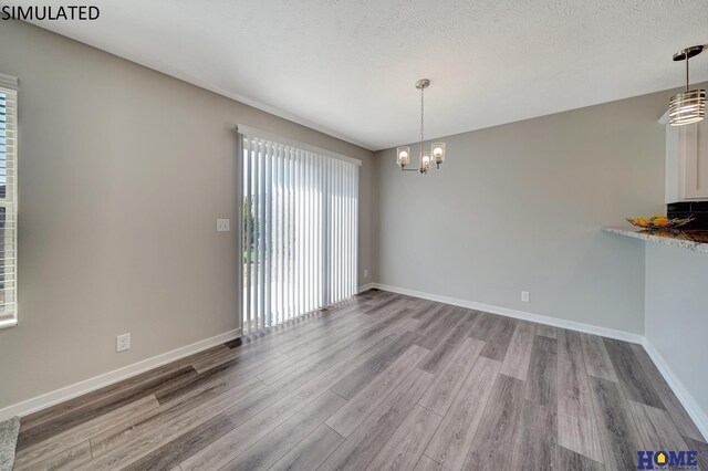 unfurnished dining area featuring a healthy amount of sunlight, light wood-type flooring, and a textured ceiling