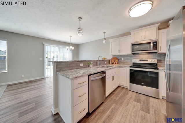 kitchen with white cabinets, hanging light fixtures, sink, light wood-type flooring, and appliances with stainless steel finishes