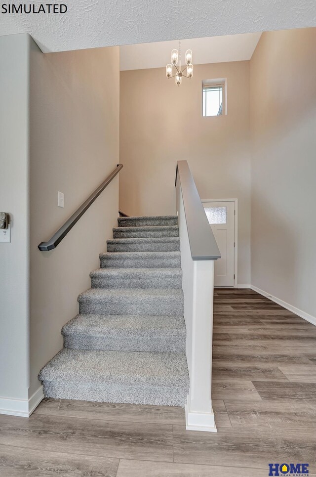 staircase with a notable chandelier, a textured ceiling, and hardwood / wood-style flooring