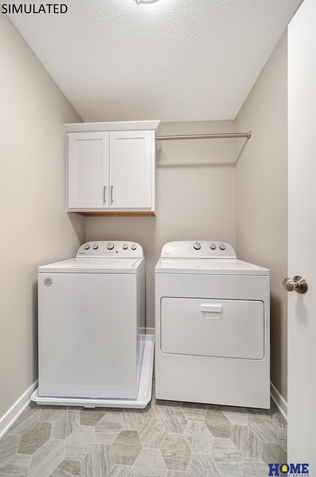 washroom featuring washer and clothes dryer, cabinets, and a textured ceiling