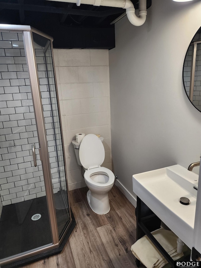 bathroom with hardwood / wood-style flooring, toilet, walk in shower, and sink