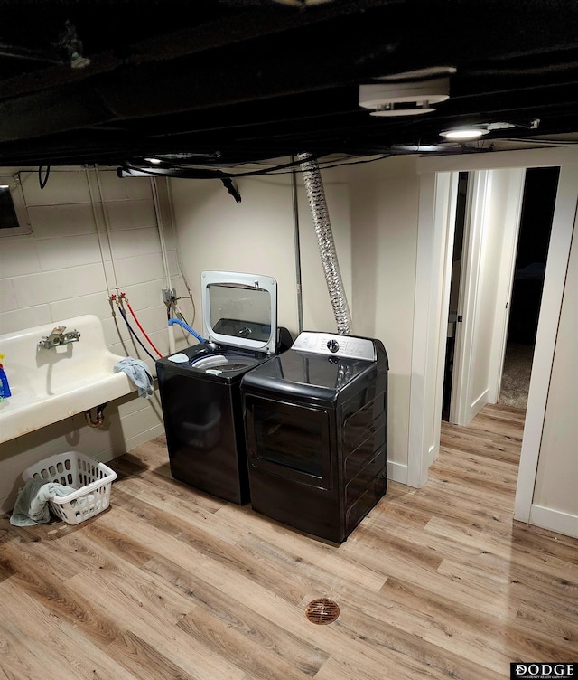 clothes washing area featuring sink, light hardwood / wood-style flooring, and washing machine and clothes dryer