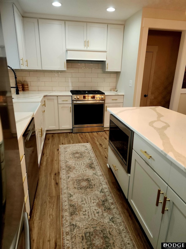 kitchen with decorative backsplash, appliances with stainless steel finishes, white cabinetry, and dark wood-type flooring