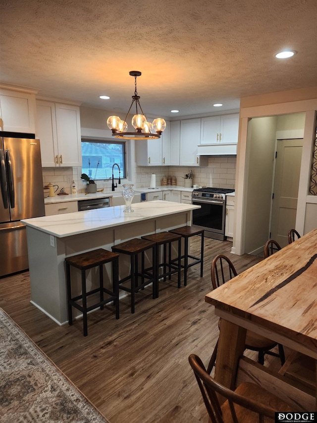 kitchen with a center island, stainless steel appliances, white cabinetry, and dark wood-type flooring